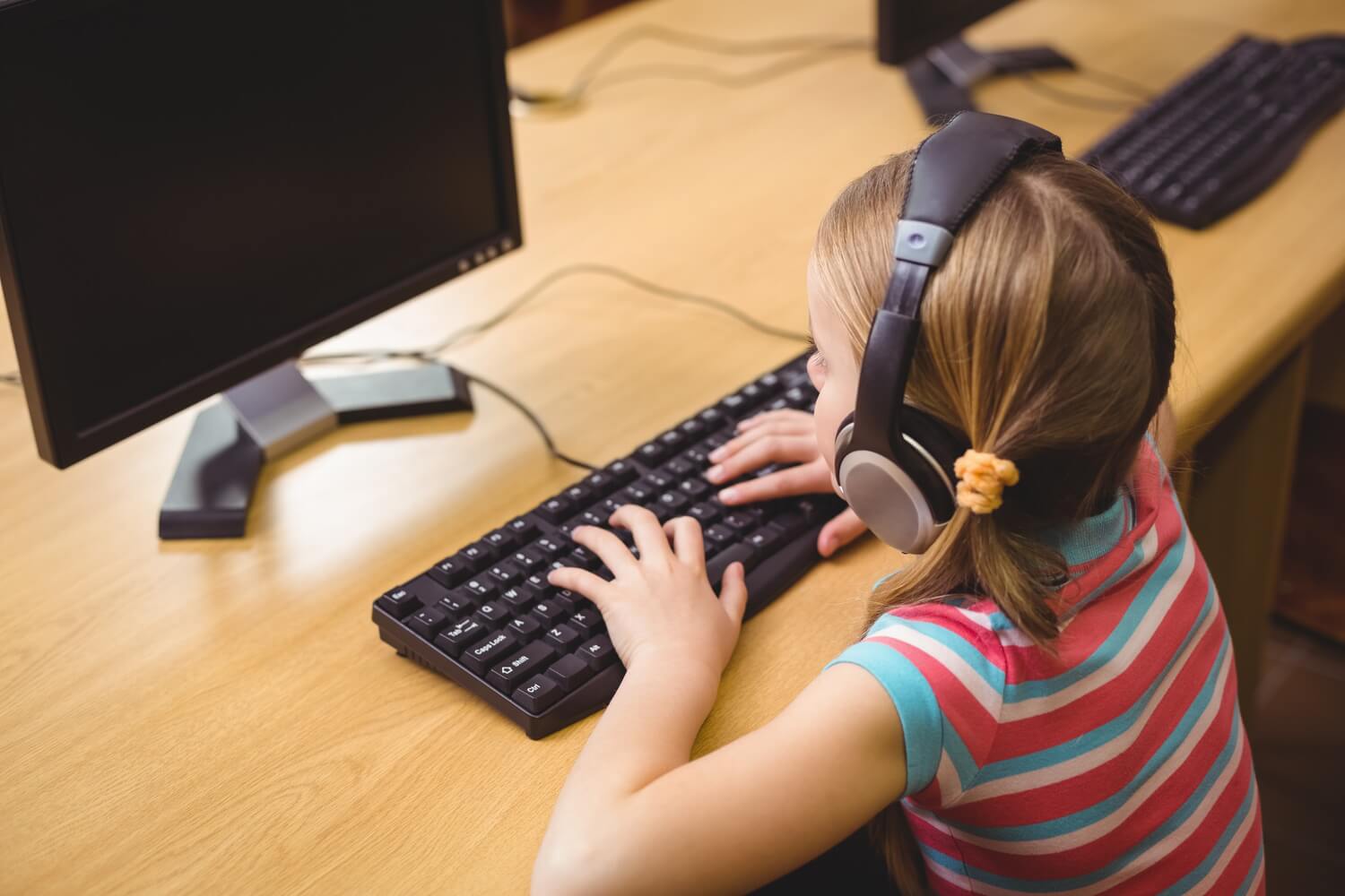 student sitting at computer table with school headphones on