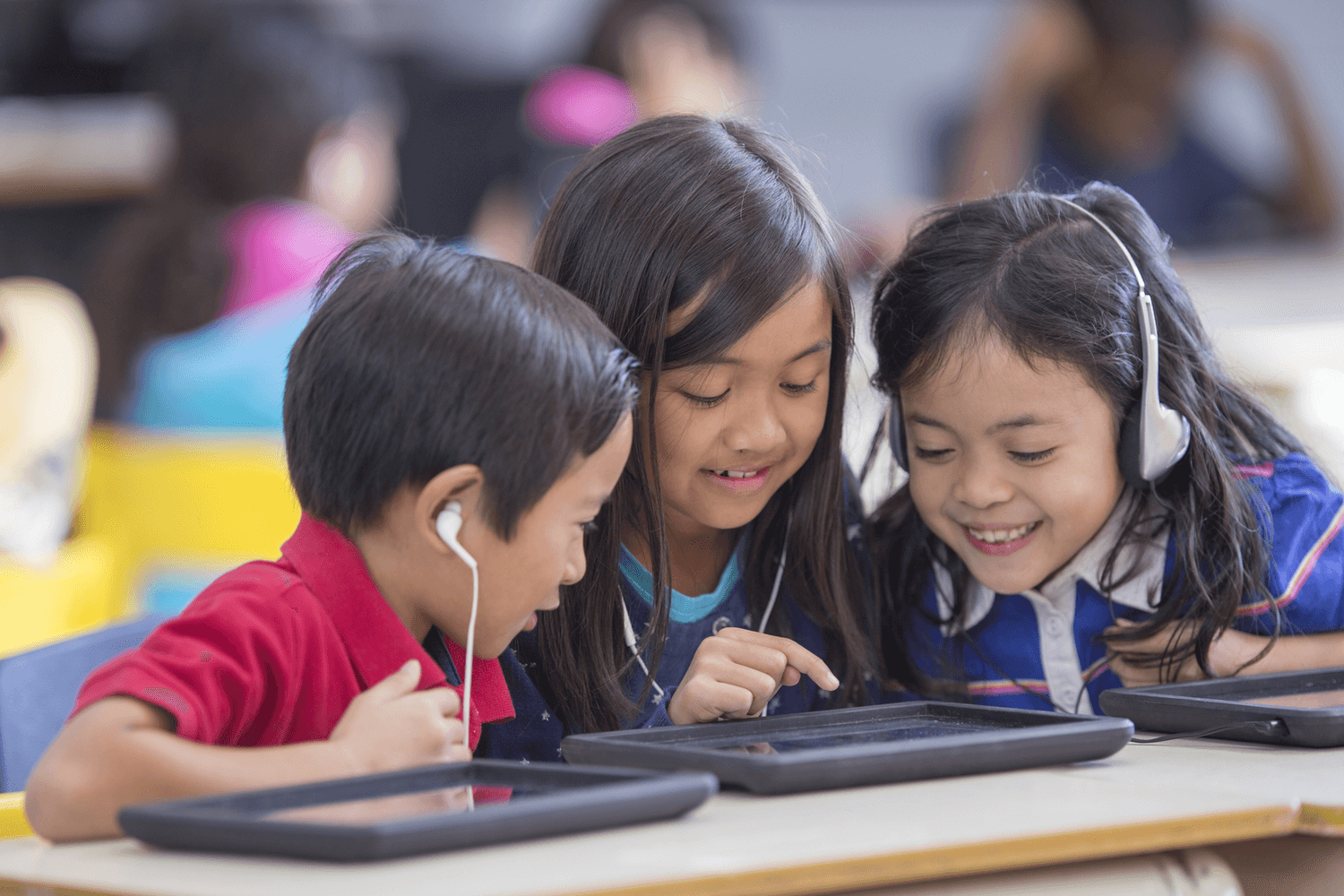 Students at desk with headphones and earbuds. School earbuds vs. school headphones – what’s the difference? Our article breaks down the five major factors to consider when purchasing new school headphones or headsets.