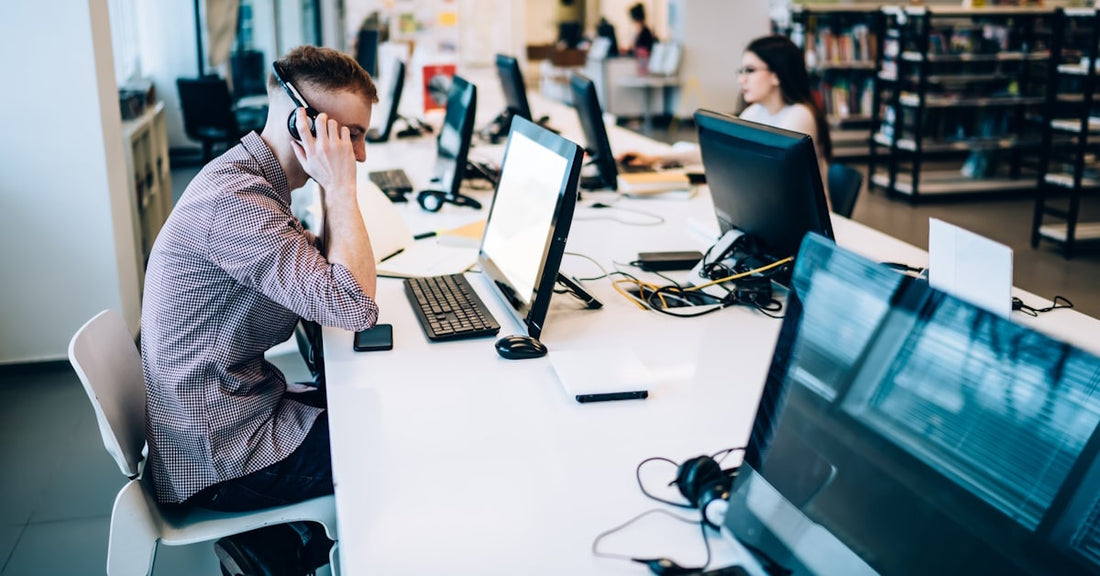 Students using desktop computers and headphones in a digital learning lab