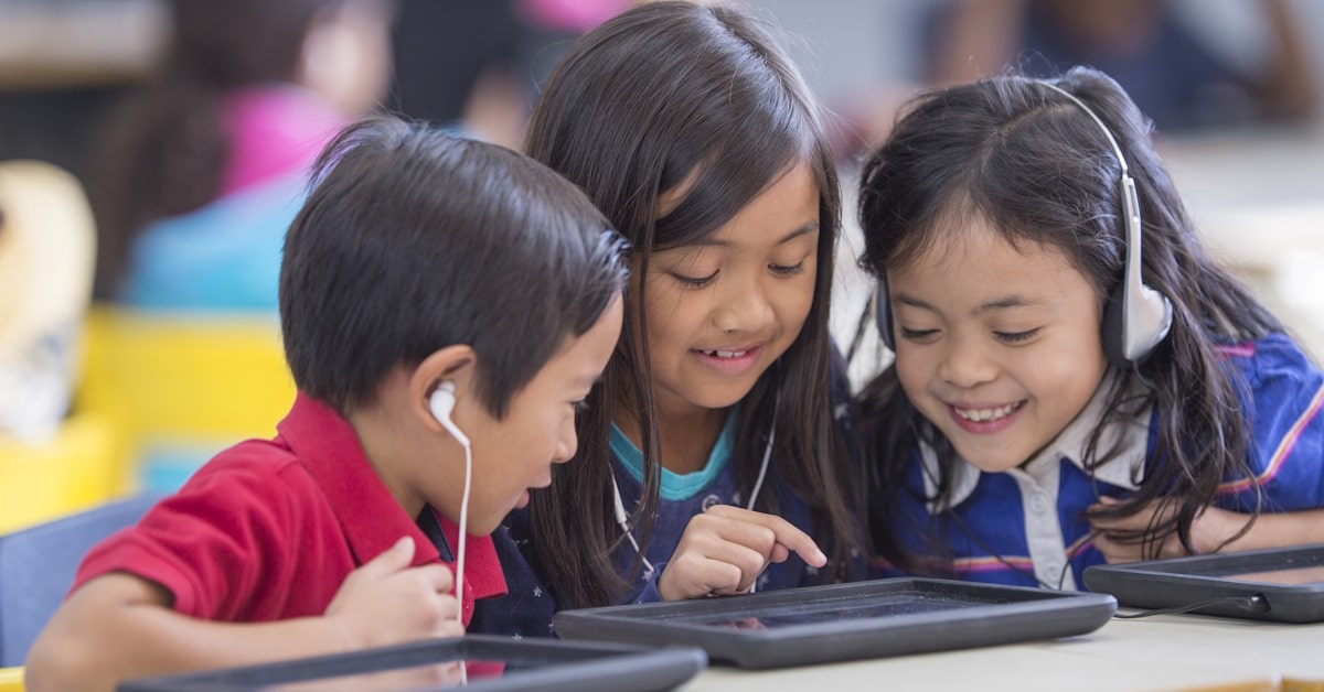 Students using a classroom listening center with tablets and shared audio equipment