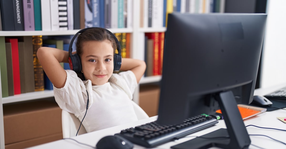 Student wearing school headphones while using a desktop computer in a classroom learning environment