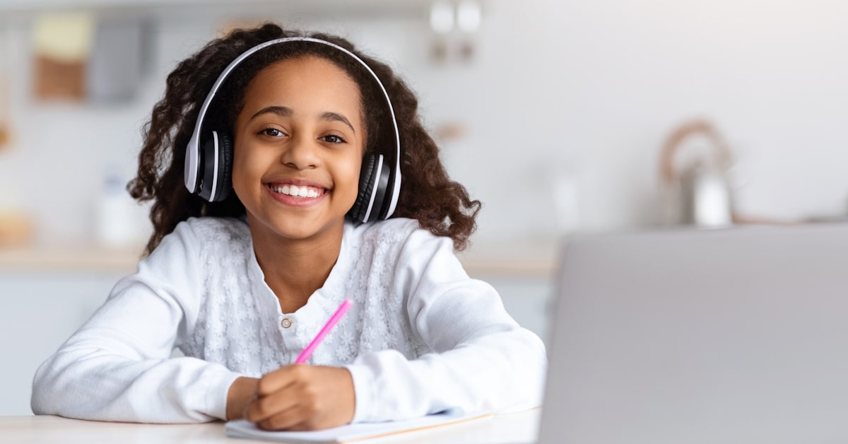 Student using wireless headphones for school learning at a laptop