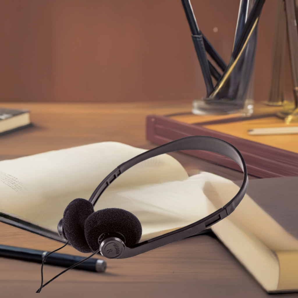 Disposable on-ear headphones on a desk with books, ideal for bulk school headphone needs in educational settings.