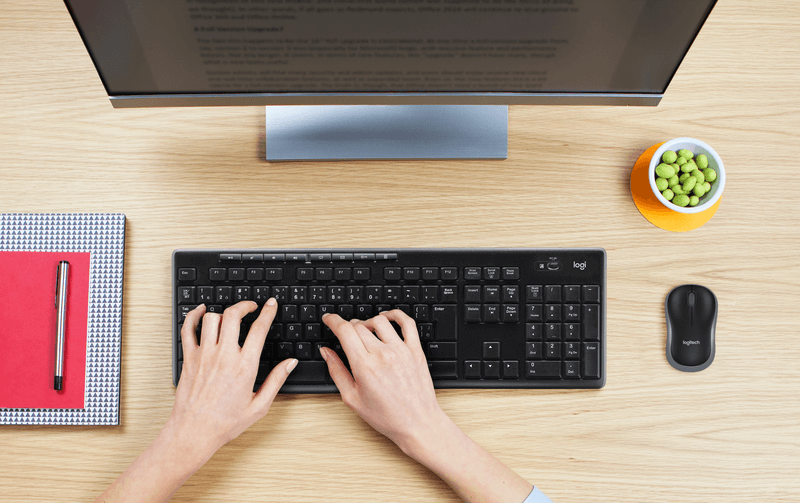 Logitech MK270 Wireless Keyboard & Mouse Combo with hands typing and monitor on a desk