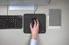 Hand using Logitech B100 optical mouse on a mousepad beside a keyboard, enhancing student productivity.