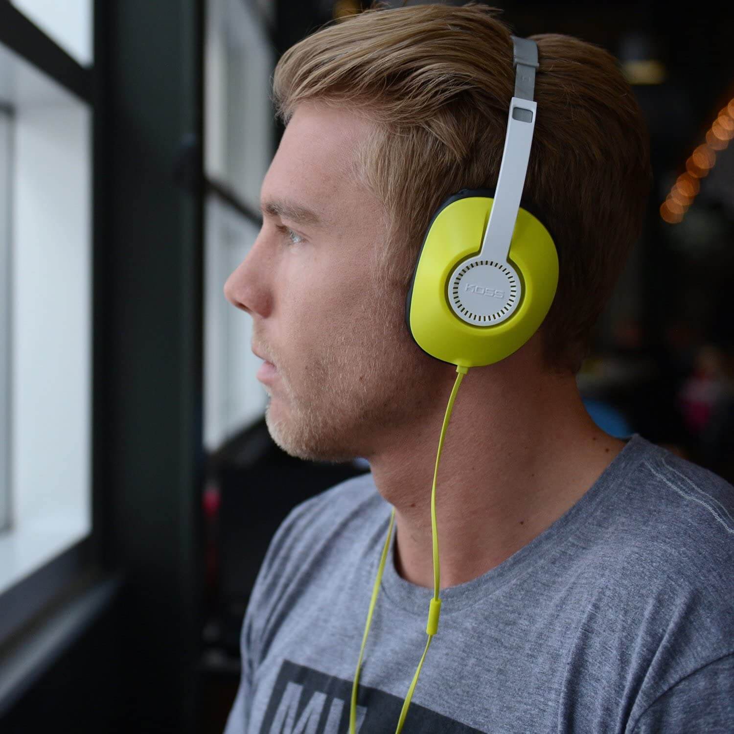 Man wearing bright yellow Koss UR23i headphones, ideal for bulk school headphones and education use.